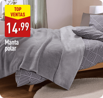 Cama con colcha de estampado geométrico en tonos grises y manta polar gris doblada sobre ella. En la parte izquierda aparece el texto Top ventas, 14,99 €, Manta polar.