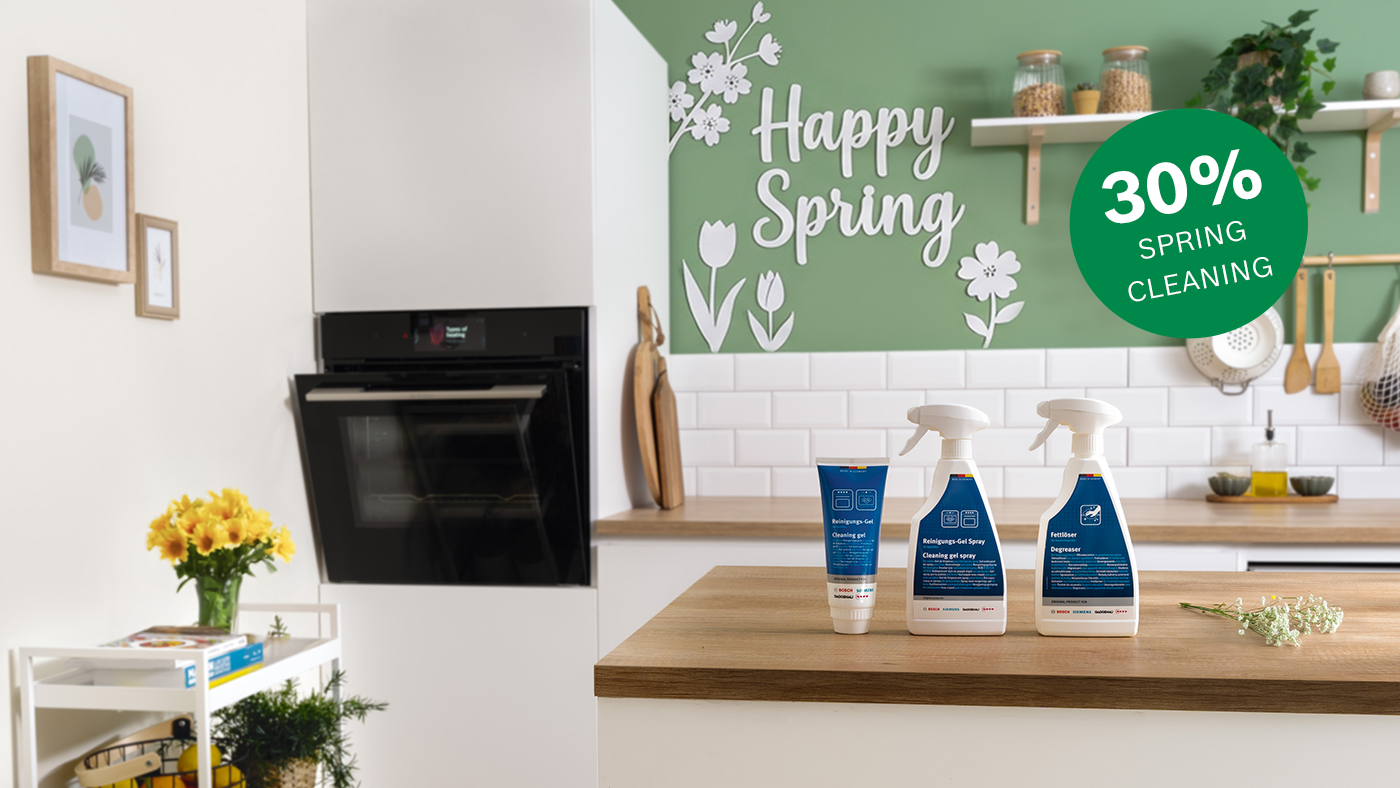 Keitti&ouml;saareke, jonka etualalla on kolme puhdistusainetta; vasemmalla sis&auml;&auml;nrakennettu uuni, valkoinen laatoitettu sein&auml; ja vihre&auml; sein&auml;koriste, jossa teksti "Hyv&auml;&auml; kev&auml;tt&auml;" ja vihre&auml; ympyr&auml;, jossa lukee "30 % kev&auml;tsiivous".