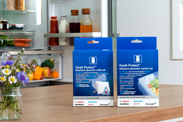 Kaksi sinist&auml; Fresh Protect -pakkausta keitti&ouml;tasolla avoimen j&auml;&auml;kaapin edess&auml;; kasviksia ja kukkakimppu vieress&auml;.