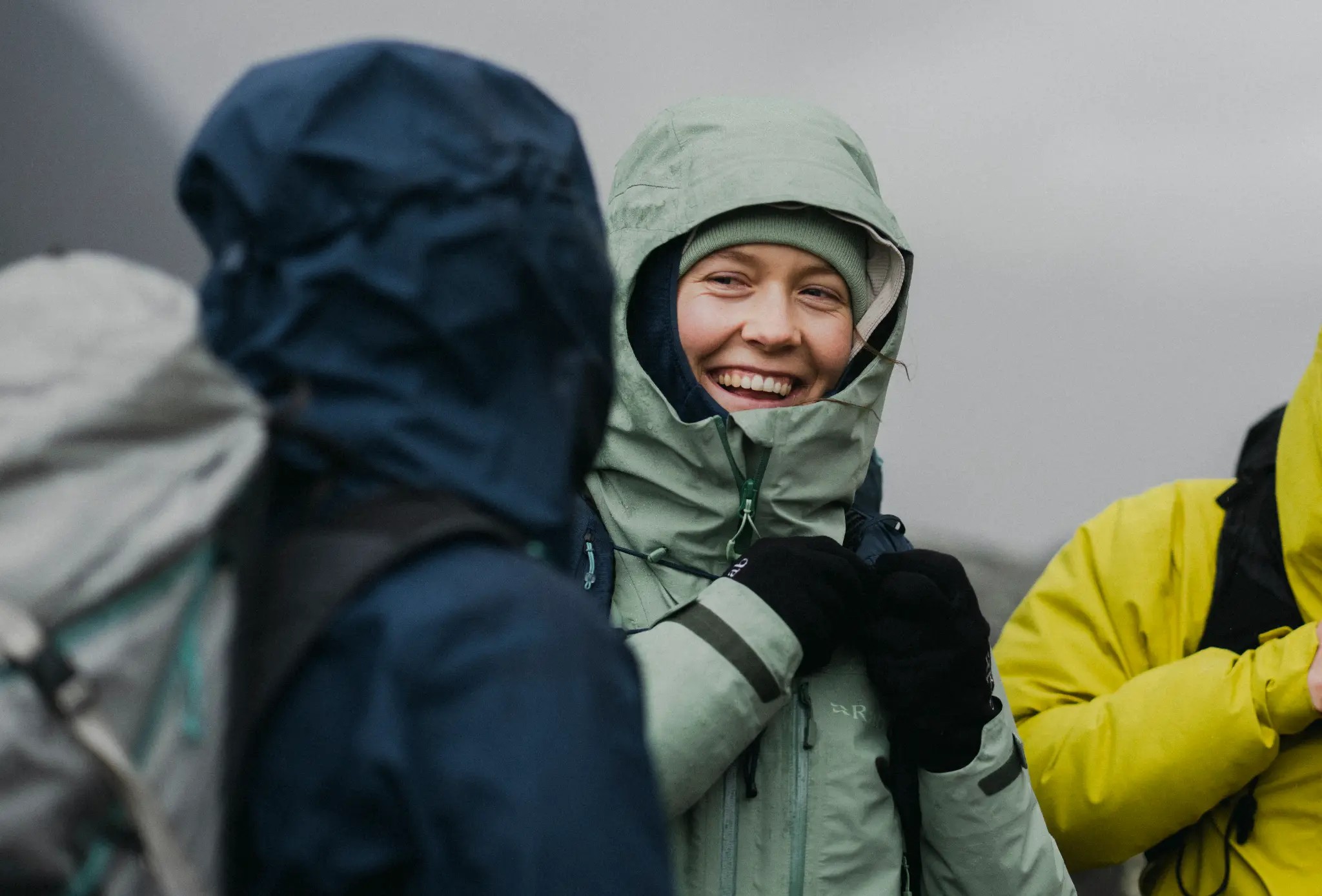 Hiker smiling in Rab Firewall Mountain Waterproof Jacket in misty mountain conditions