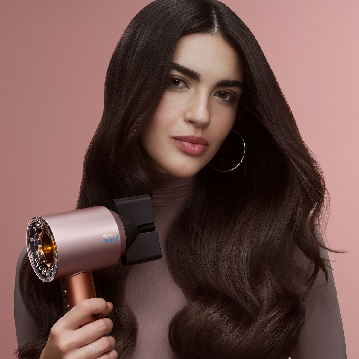 A model blow dries her hair with the Dyson Supersonic Nural hair dryer.