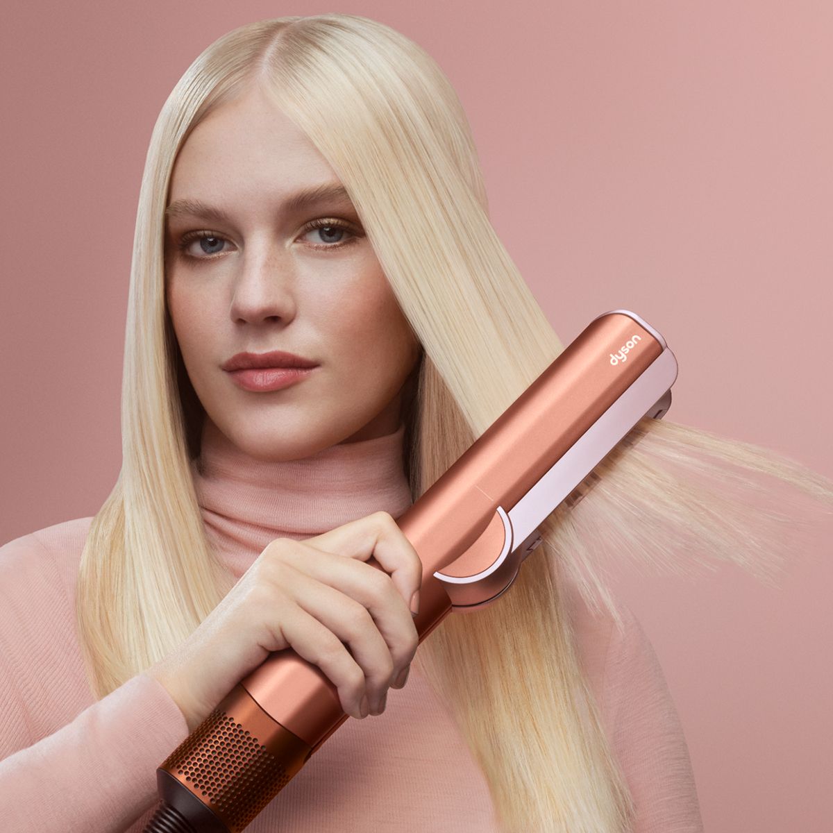 A model smooths and straightens her hair with the Dyson Airstrait dryer and straightener.