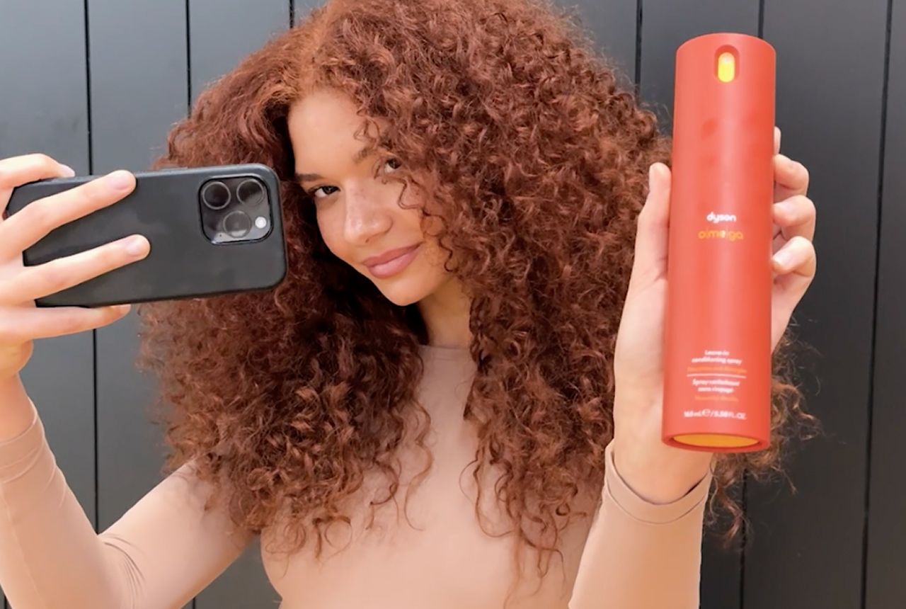 Una modelo de pelo rizado con el cabello nutrido con productos Dyson Omega.