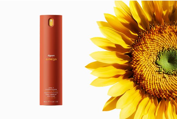 Acondicionador Dyson Omega sin aclarado en espray junto a un girasol.
