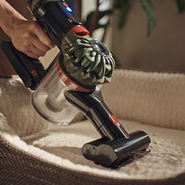 La aspiradora Dyson V8 Cyclone se utiliza con el minicepillo motorizado para limpiar la cama de una mascota.