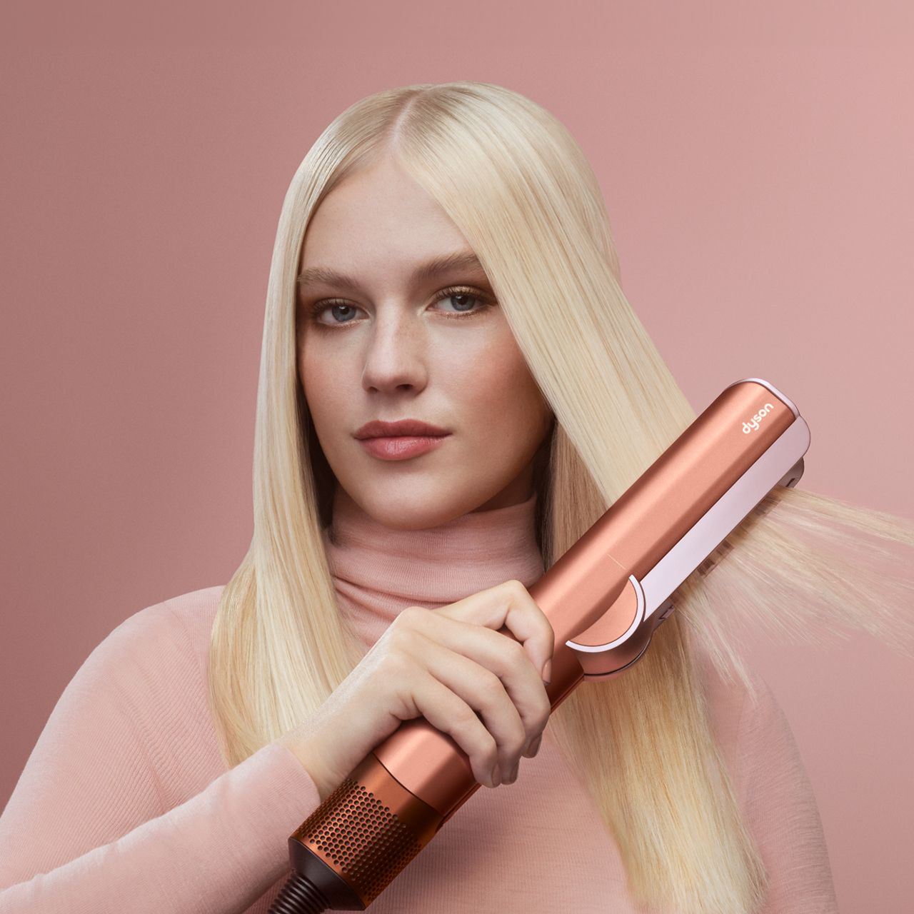 Model holds the Dyson Supersonic Nural hair dryer in Amber silk.