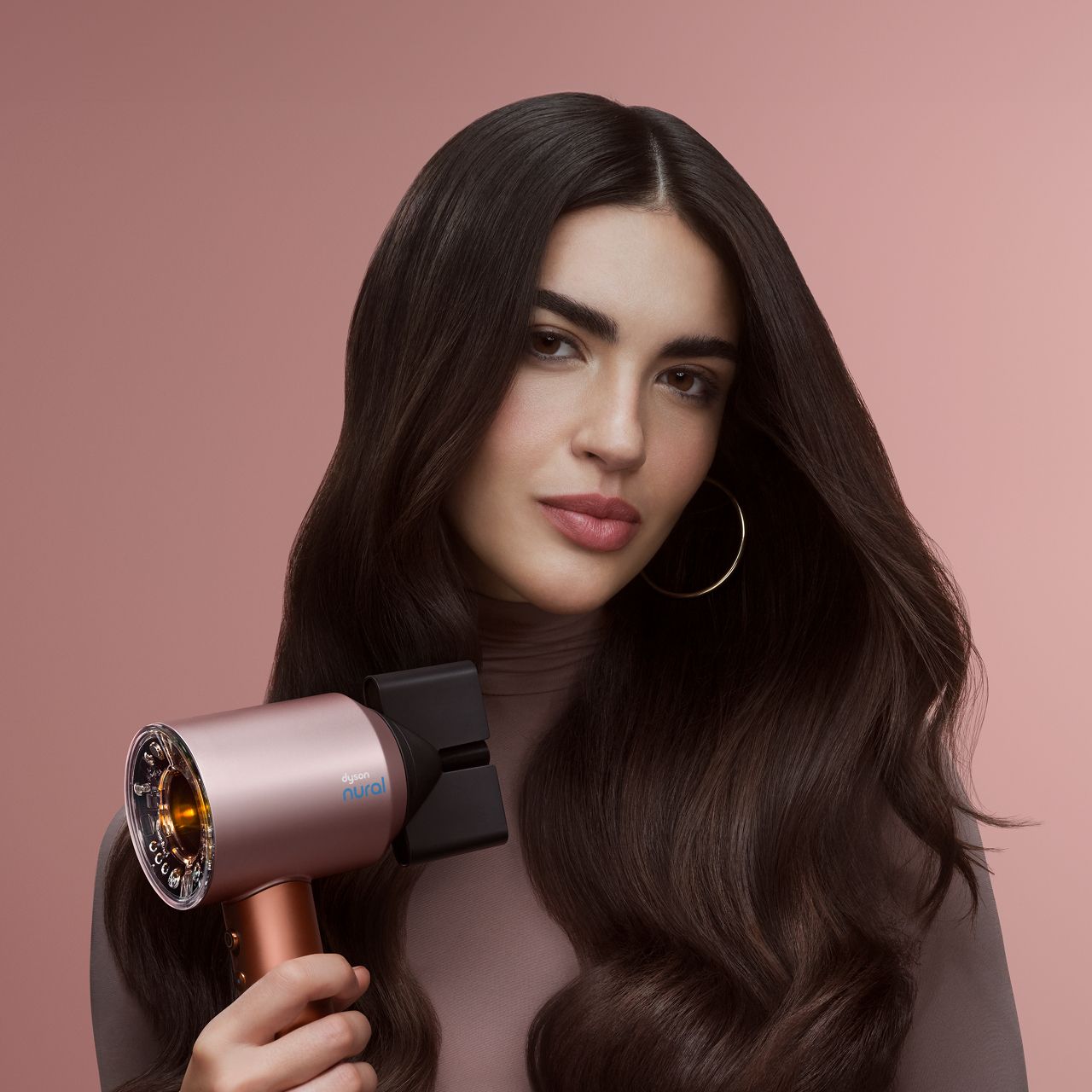 Model holds the Dyson Airstrait dryer and straightener in Amber silk.