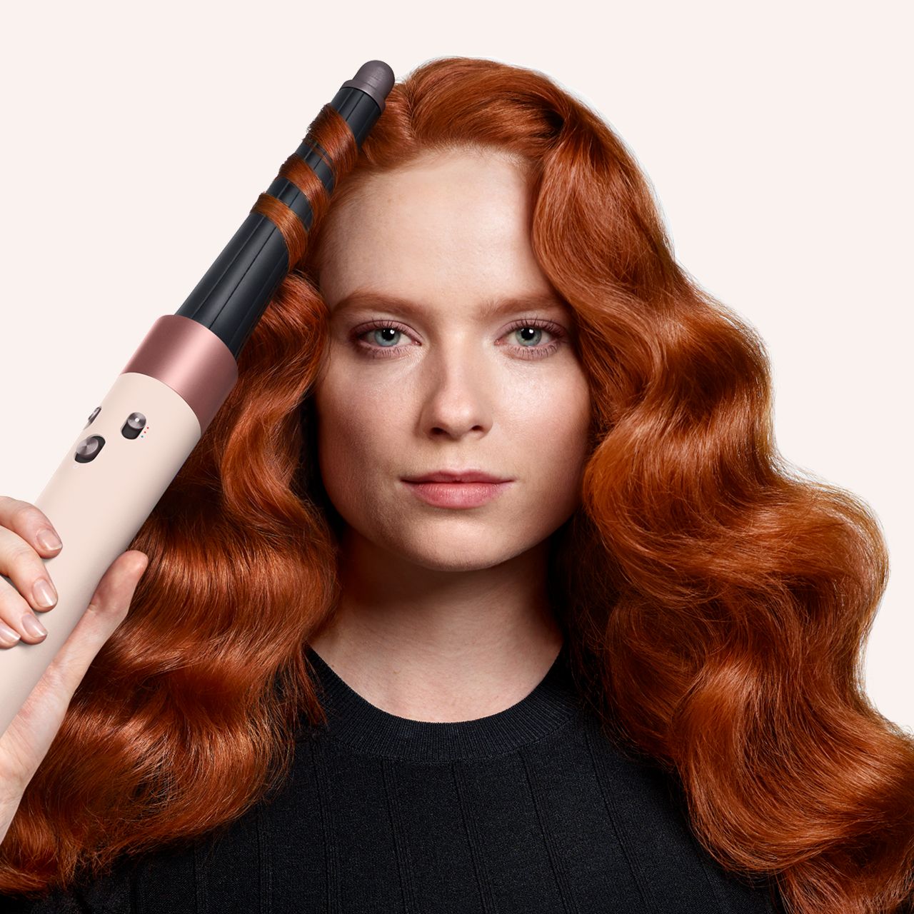 Model smooths and dries her hair with the Dyson Airstrait dryer and straightener in Ceramic pink and rose gold.