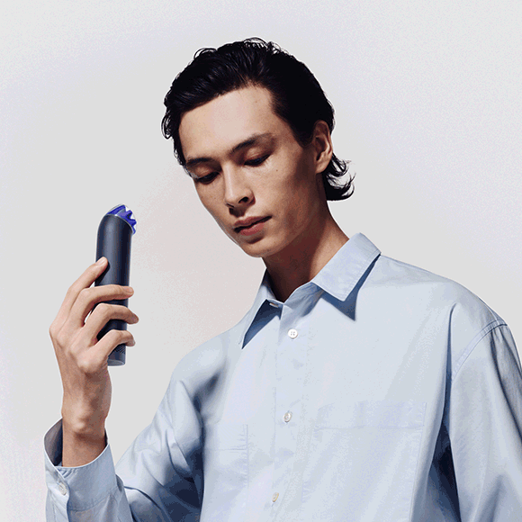 Dyson HushJet Mini Cool fan held in a hand, worn in the Neck Dock and stood on the Charging Stand.