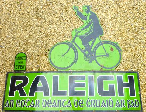 Raleigh. A large three piece wall-mounted enamel sign with Gaelic text, ‘An Rotar Oeanta oe Cruaio Ar Fao’. (Raleigh all steel Bicycle)