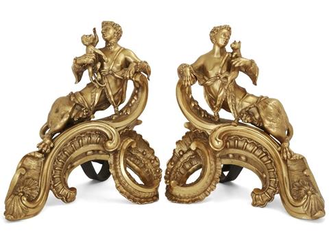 A pair of French ormolu chenets, 19th century, after a model by Charles Cressent, French, 1685-1768, each with a sphinx partially covered by drapery and holding a cat and monkey respectively