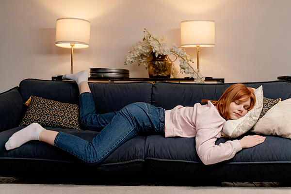 Person sleeping on a couch with cozy decor.