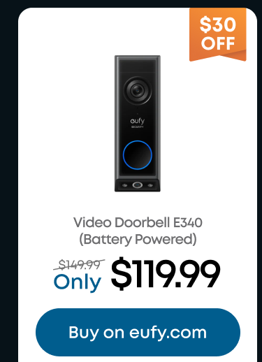 Man in a gray blazer over a dark gray shirt standing on stairs in an urban background.