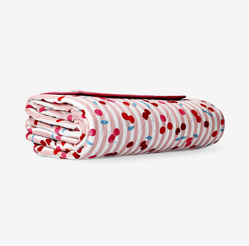 Quilted picnic blanket with berry print and carrying strap