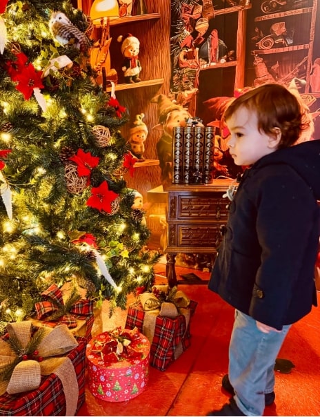 Criança a olhar para os presentes na árvore de natal