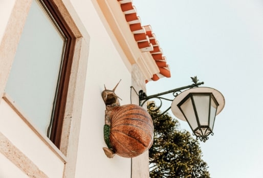 Escultura de um caracol gigante a subir a fachada de uma casa