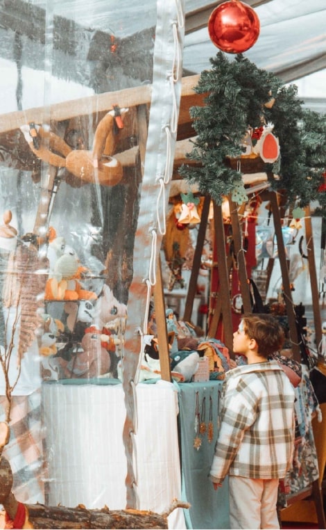 Criança a olhar para uma banca de um mercado de Natal