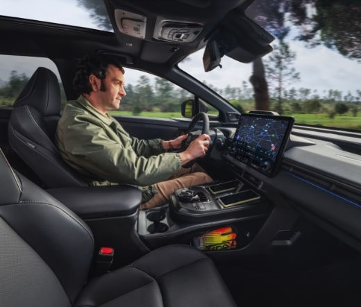 Condutor com ar confiante, ao volante do Toyota bZ4X com ecrã multimédia visível no interior.