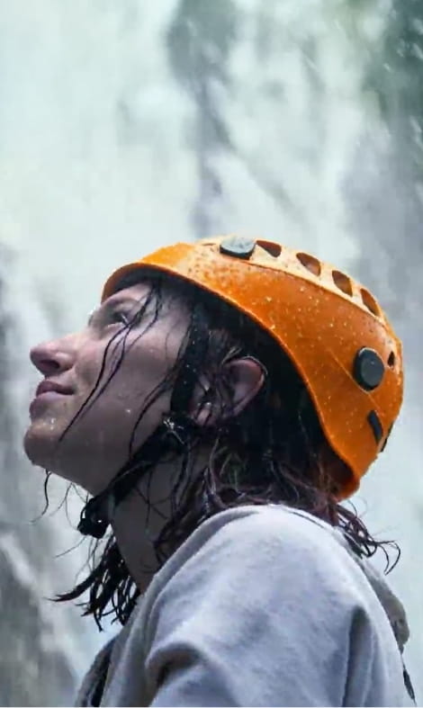 Mulher a escalar à chuva com um capacete cor de laranja