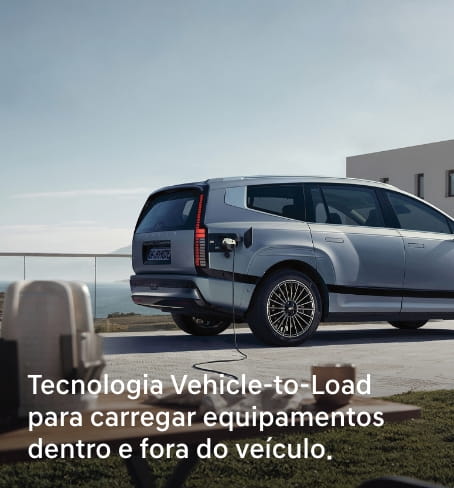 Hyundai IONIQ 9 prateado ligado a equipamento externo com cabo, com texto sobre tecnologia Vehicle-to-Load.