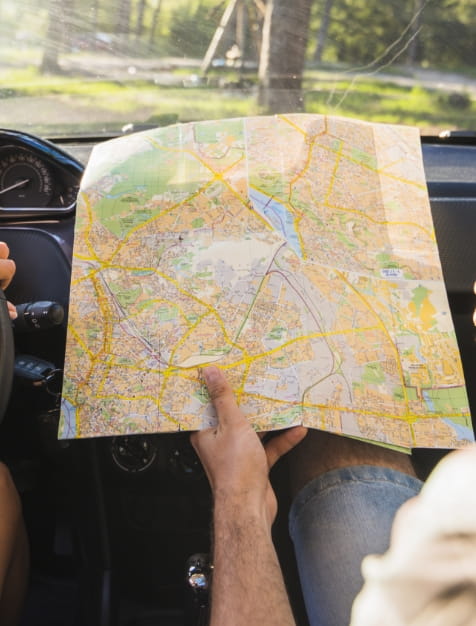 Mão a segurar num mapa aberto com na região Centro de Portugal, dentro de um carro