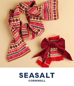 Seasalt Cornwall: Knitted scarf and gloves with colorful patterns, red accents, and a large burgundy bow on gloves. Light background with "Seasalt Cornwall" text.