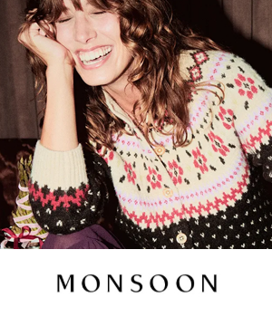 Monsoon: A woman with curly hair is laughing joyfully, wearing a patterned knit sweater with floral and geometric designs. The mood is warm and cheerful.