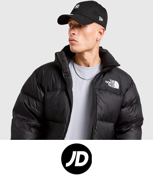 JD Sports - A person in a black The North Face puffer jacket and cap looks to the side on a grey background