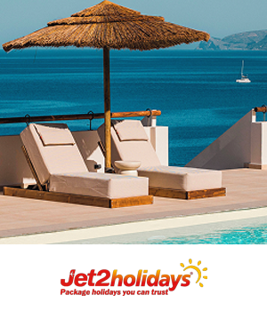Jet2 Holidays: Two sun loungers under a straw parasol facing a tranquil blue sea on a sunny deck.