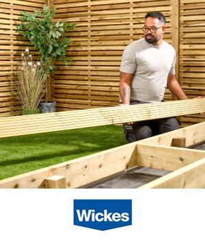 Wickes - Man holding timber deck board whilst renovating garden