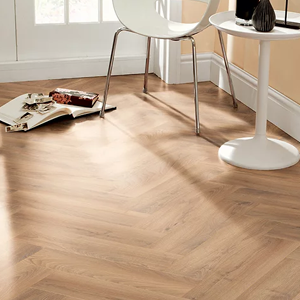 Modern interior with light wood herringbone floor, a white round table, and chair.