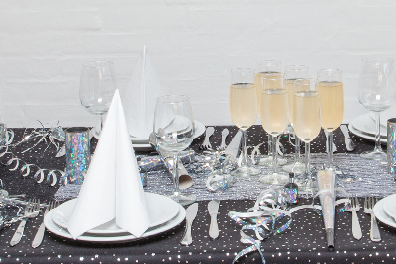 Bild på ett vackert dekorerat nyårsbord med champagneglas, bestick och servis