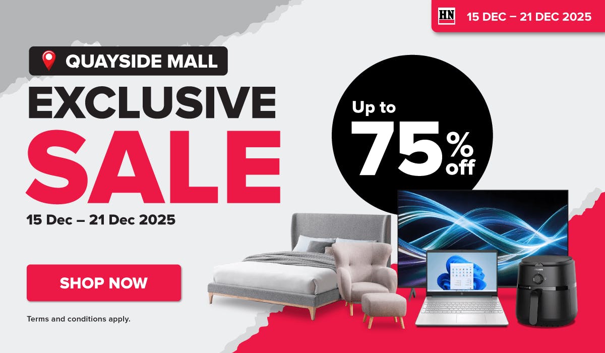 Man in a gray blazer over a dark gray shirt standing on stairs in an urban background.