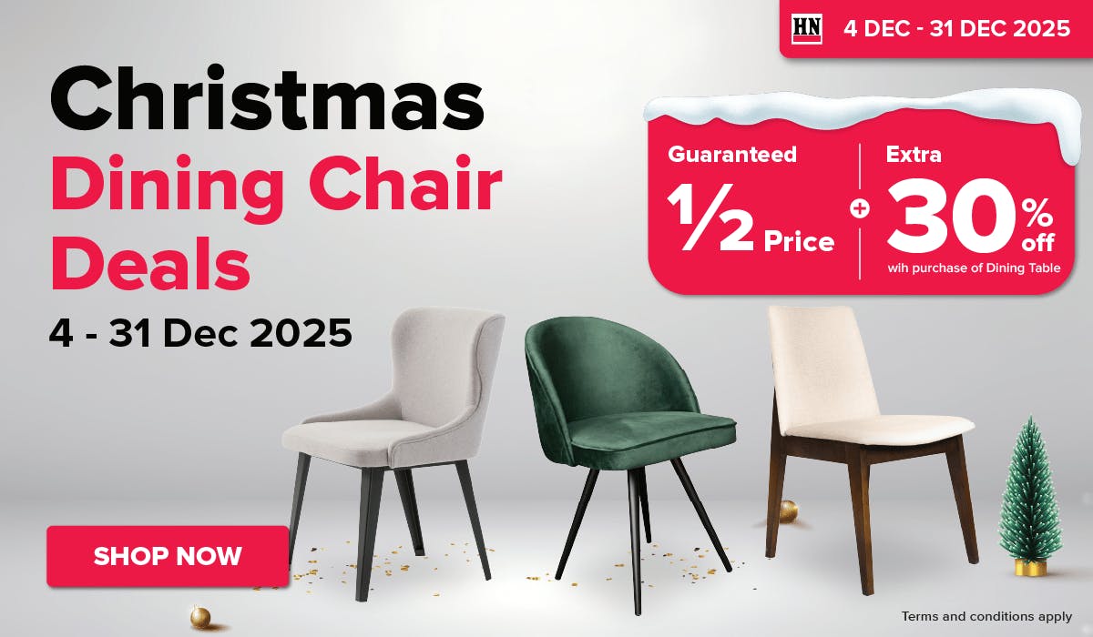 Man in a gray blazer over a dark gray shirt standing on stairs in an urban background.