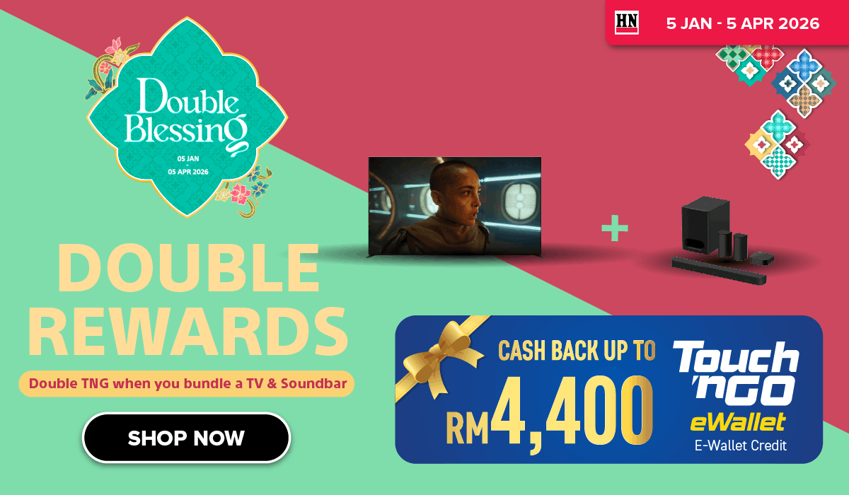 Man in a gray blazer over a dark gray shirt standing on stairs in an urban background.