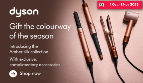 Woman wearing an olive green blazer and light blue jeans walking in an urban setting.