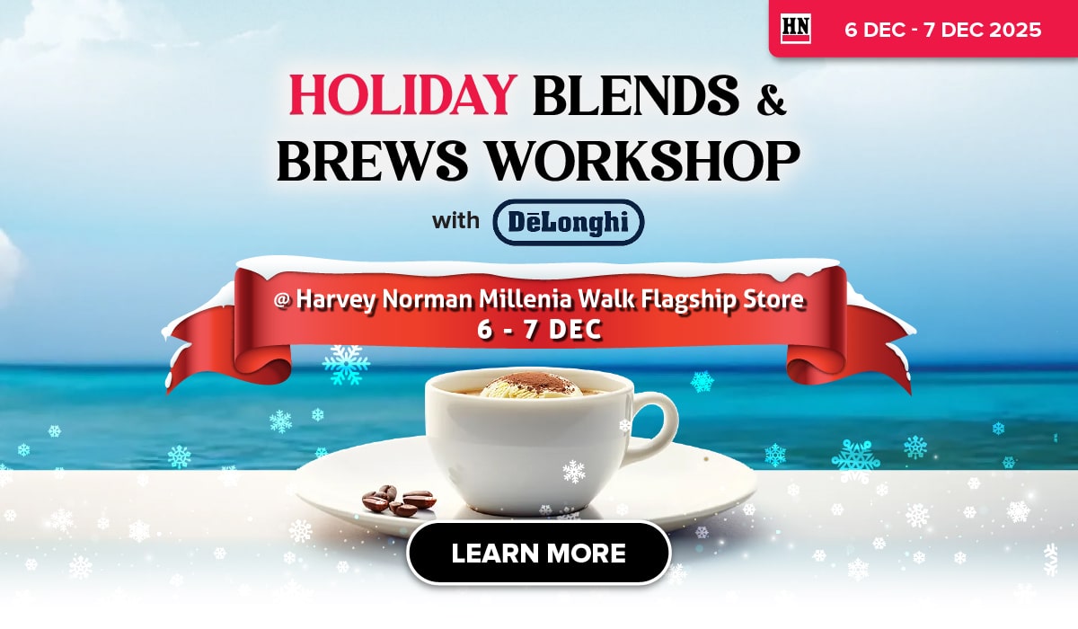 Man in a gray blazer over a dark gray shirt standing on stairs in an urban background.