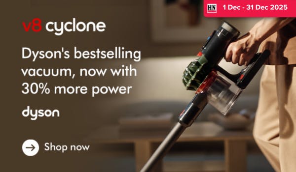 Woman wearing an olive green blazer and light blue jeans walking in an urban setting.