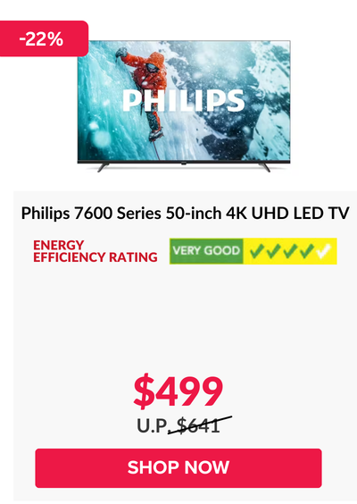 Man in a gray blazer over a dark gray shirt standing on stairs in an urban background.