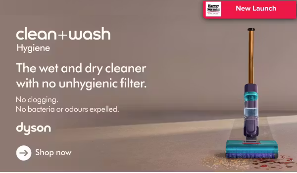 Man in a gray blazer over a dark gray shirt standing on stairs in an urban background.