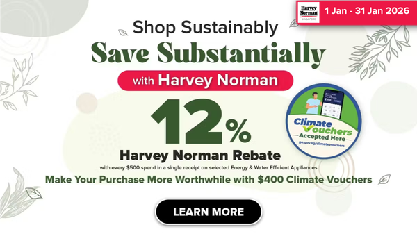 Man in a gray blazer over a dark gray shirt standing on stairs in an urban background.