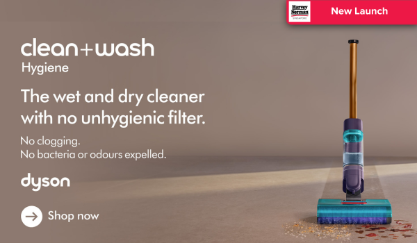 Man in a gray blazer over a dark gray shirt standing on stairs in an urban background.