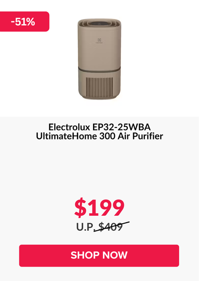 Man in a gray blazer over a dark gray shirt standing on stairs in an urban background.