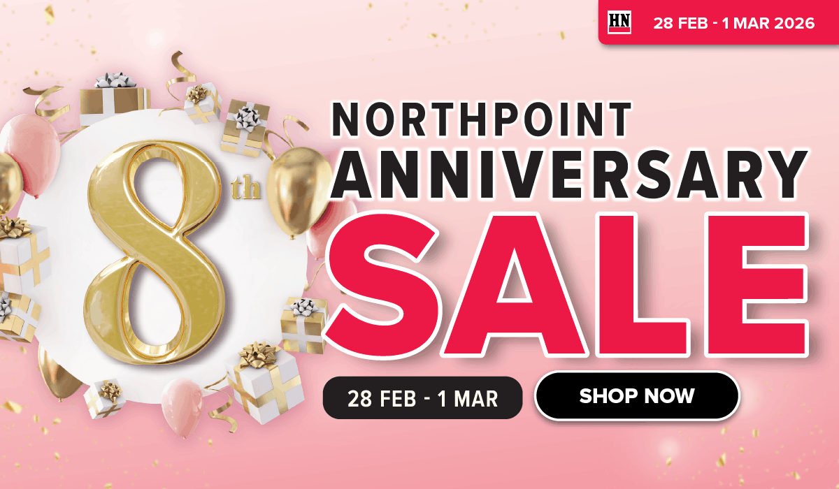 Man in a gray blazer over a dark gray shirt standing on stairs in an urban background.