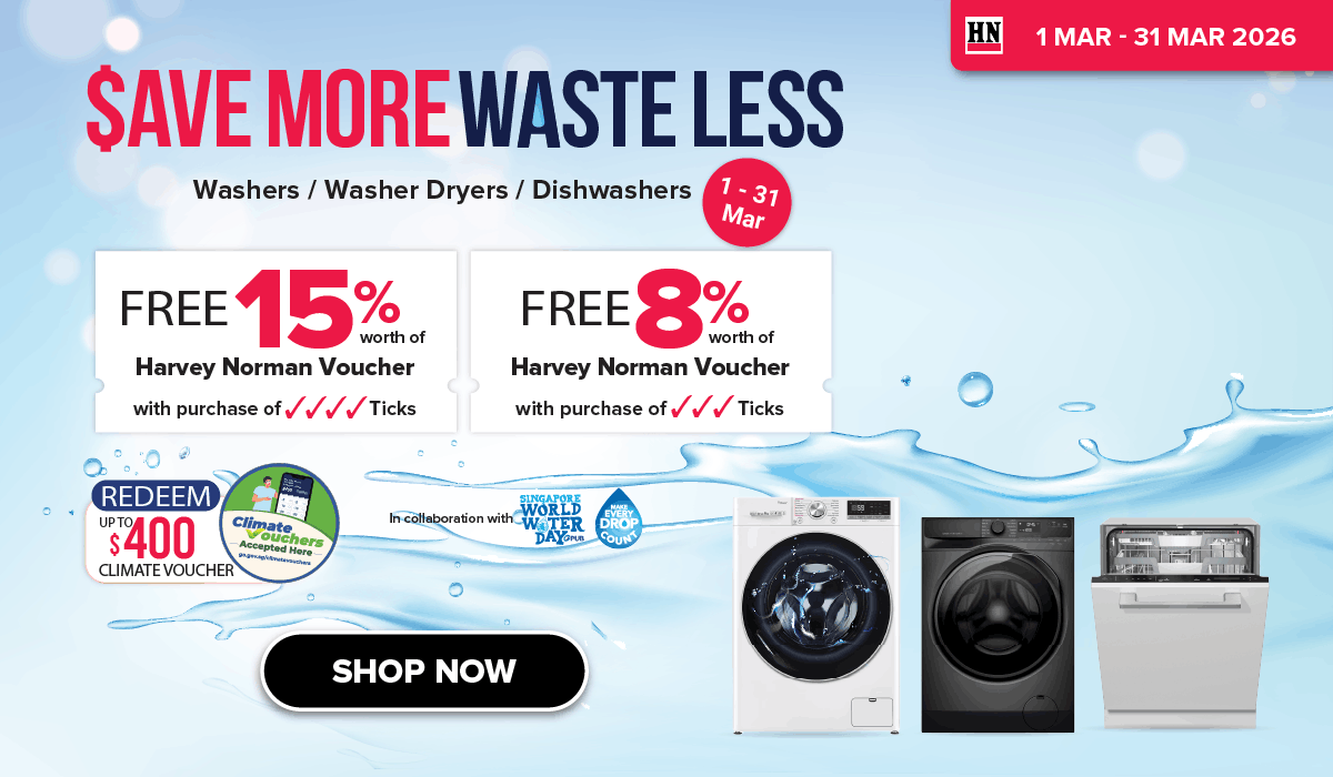 Man in a gray blazer over a dark gray shirt standing on stairs in an urban background.