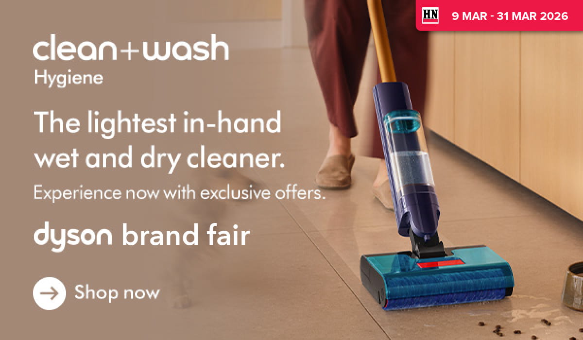 Woman wearing an olive green blazer and light blue jeans walking in an urban setting.