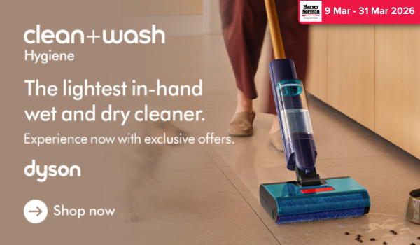 Woman wearing an olive green blazer and light blue jeans walking in an urban setting.