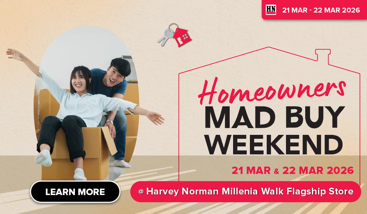 Man in a gray blazer over a dark gray shirt standing on stairs in an urban background.