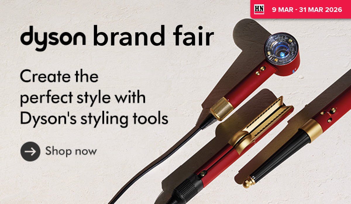 Woman wearing an olive green blazer and light blue jeans walking in an urban setting.