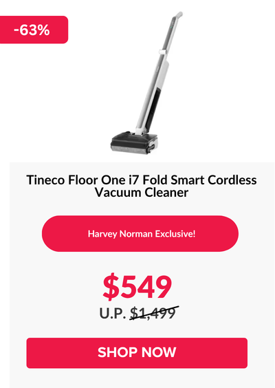 Woman wearing an olive green blazer and light blue jeans walking in an urban setting.